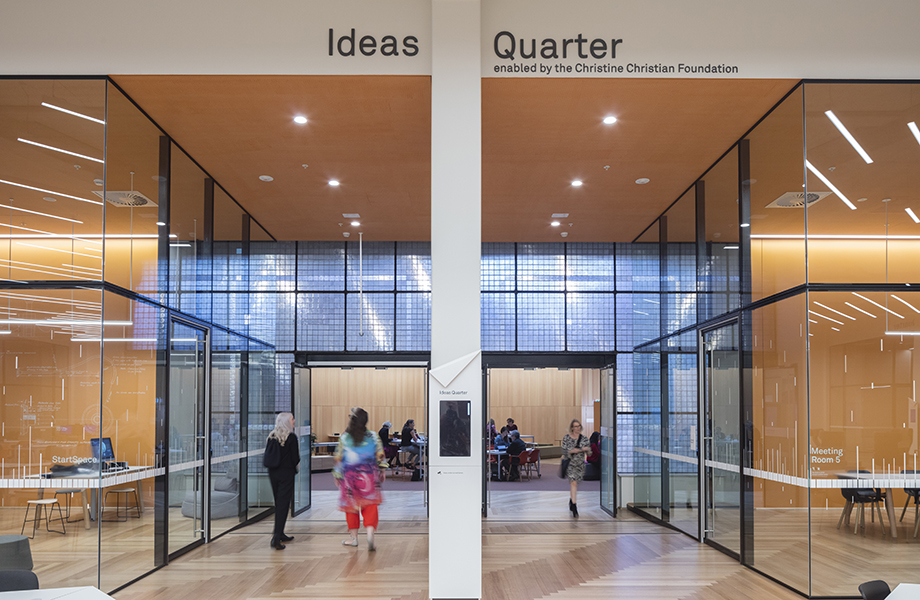 Two women walk into StartSpace and more people can be seen working inside.